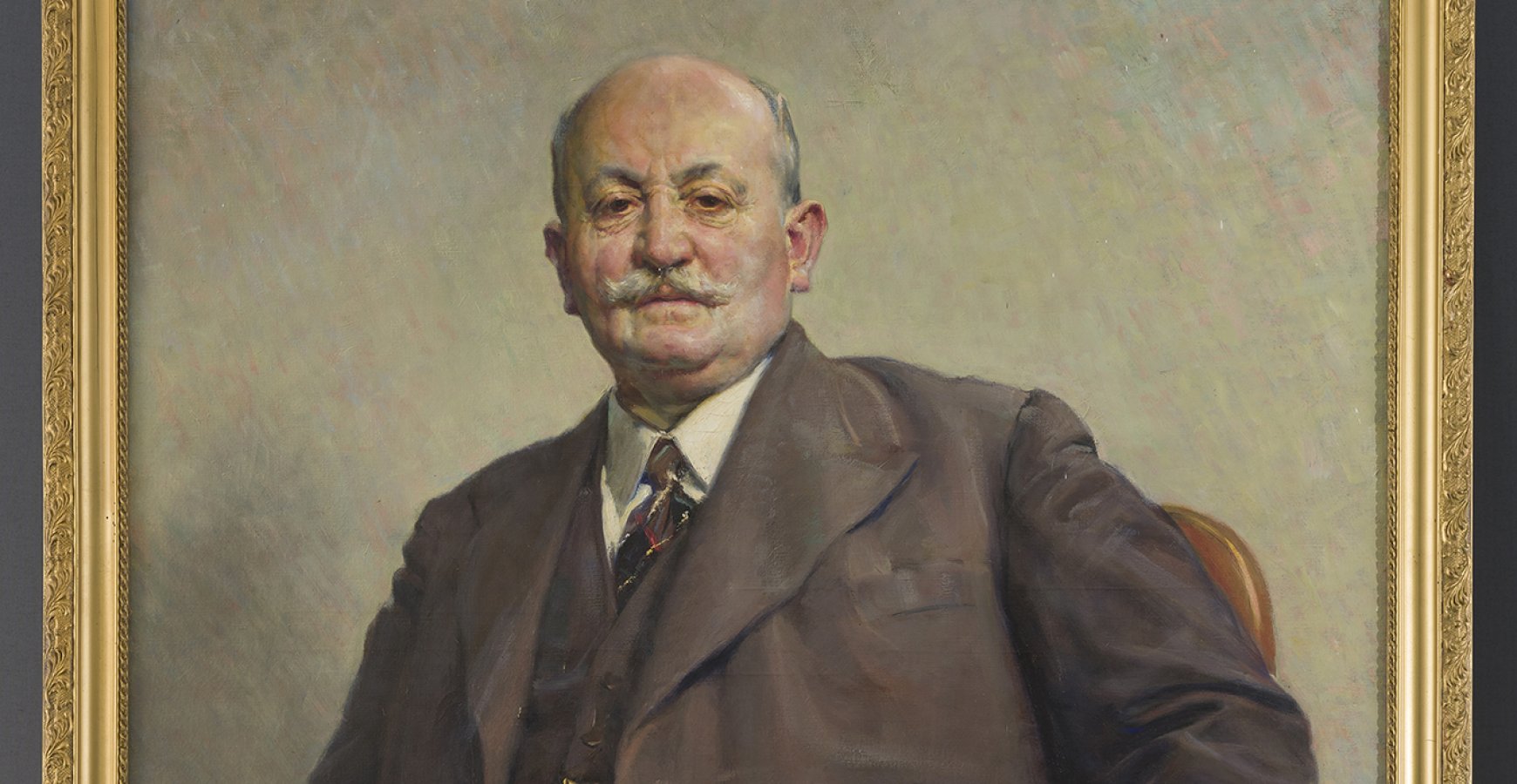  photo of the subject, portrait of a seated middle-aged man with a mustache, dressed in a gray and brown suit