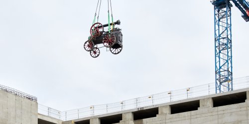 photo of locomobile being transported by crane